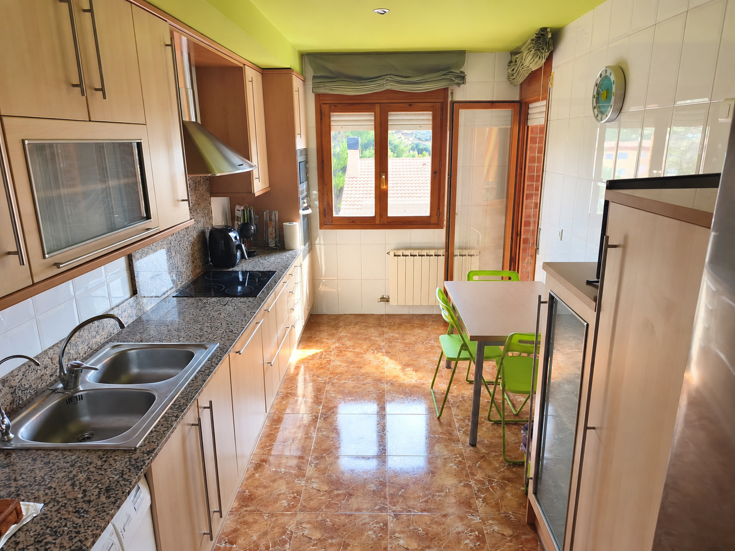 Cocina moderna con mesa despejada y sillas verdes